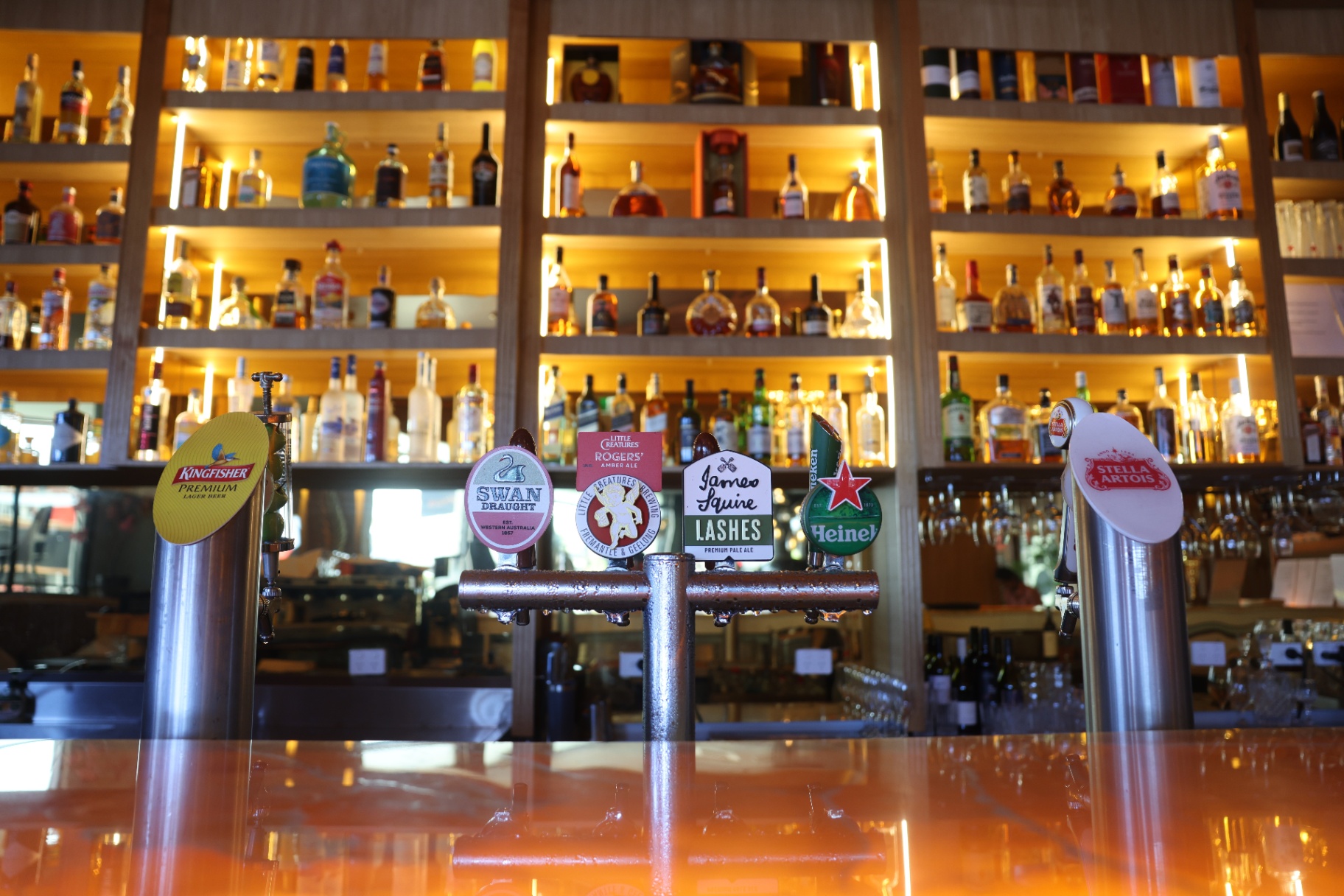 Beer taps against the illuminated spirits wall